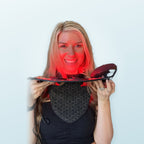 Smiling woman holding the lit mask, wearing the neck piece